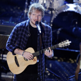Ed Sheeran cântă la chitară îmbrăcat cu o cămașă albastră în unul dintre cele 10 momente memorabile.