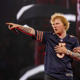 Ed Sheeran anunță albumul de toamnă. Aici este pe scenă la un concert. Poartă un tricou albastru cu dungi portocalii și arată către public.