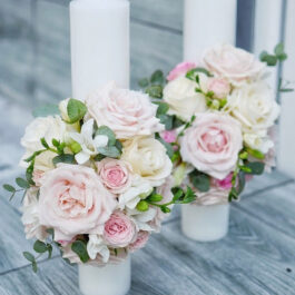 Florile ca decor pentru ceremonia religioasă. Două lumânăro de botez, albe, decorate cu buchete de flori roz și albe