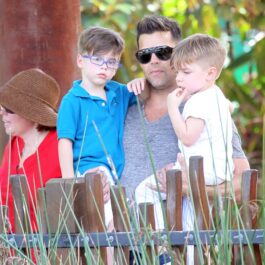 Gemenii lui Ricky Martin sunt în brațe la tatăl lor celebru. Unul poartă ochelari și un tricou albastru, iar celălalt un tricou alb. Ambii se uită la animalele de la zoo