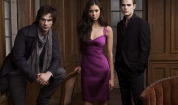 Actorii din The Vampire Diaries, unul dintre acele seriale de dragoste iubite de mulți, sunt în fața unei camere de luat vederi. Cei doi frați vampiri sunt îmbrăcați în costume elegante, iar ea poartă o rochie mov decoltată și extrem de sexy.