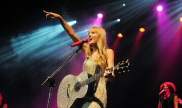 Taylor Swift este pe scenă, cu chitara în mână. Poartă o rochie aurie, mulată și lungă care îi scoate în evidență trupul. Părul este lăsat pe spate și puțin ondulat.