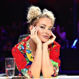 Delia, cu părul prin în două cocuri laterale și îmbrăcată cu o bluza roșie, înflorată, stă la masa juriului X Factor