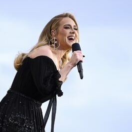 Adele îmbrăcată într-o rochie neagră în timp ce cântă la microfon