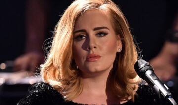 Adele machiata si aranjata, cu parul pe spate, îmbrăcată în negru