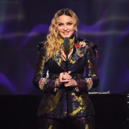 Madonna machiată și îmbrăcată elegant într-un costum colorat, cu un papion la gât