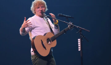 Ed Sheeran, pe scenă, cu chitara și cu microfonul alături