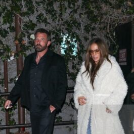 Jennifer Lopez, îmbrăcată cu un palton alb pufos, și Ben Affleck, îmbrăcat într-un costum negru, mergând împreună
