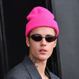 Justin Bieber a ajutat un om al străzii. Aici este la un eveniment și poartă un sacou gri închis, o căciulă roz aprins și ochelari de soare