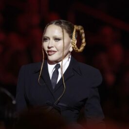 Madonna, cu o coafură excentrică din două cozi împletite, îmbrăcată în cămașă albă cu cravata și sacou negru