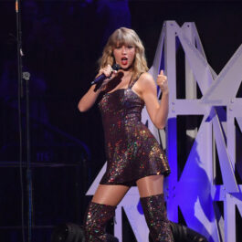 Taylor Swift a lansat albumul „1989 (Versiunea lui Taylor)”. Aici este pe scenă. Poartă o rochie scurtă, vișinie și cizme peste genunchi din același material