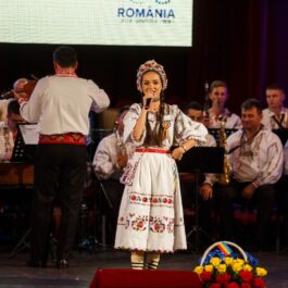 Vlăduța Lupău, în costum popular, pe scenă, alături de orchestră