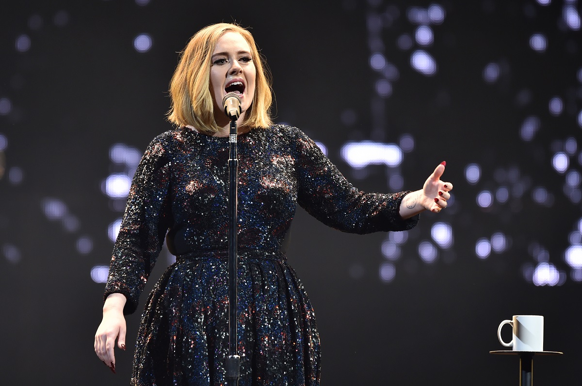 Adele îmbrăcată într-o rochie neagră strălucitoare în timp ce cântă