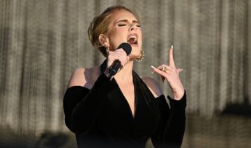 Adele în timp fredonează o melodie și gesticulează din mâini