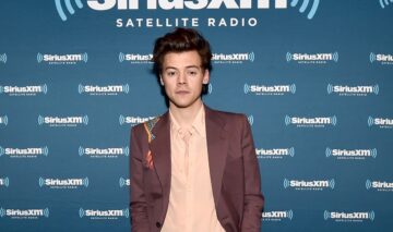 Harry Styles îmbrăcat cu un costum maro