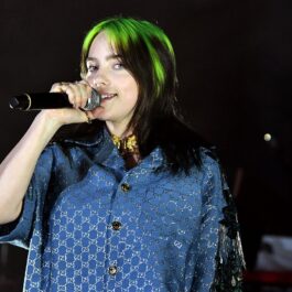 Billie Eilish vopsită în două culori în timp ce cântă la microfon