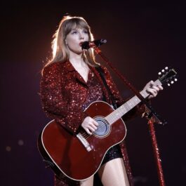 Taylor Swift îmbrăcată în roșu cântând atât cu vocea cât și la chitară
