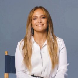 Jennifer Lopez zâmbind în timp ce poartă o cămașă albă