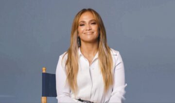 Jennifer Lopez zâmbind în timp ce poartă o cămașă albă