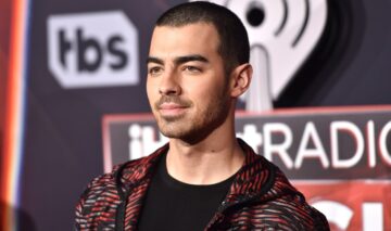 Joe Jonas tuns scurt purtând un tricou negru și o bluză de training