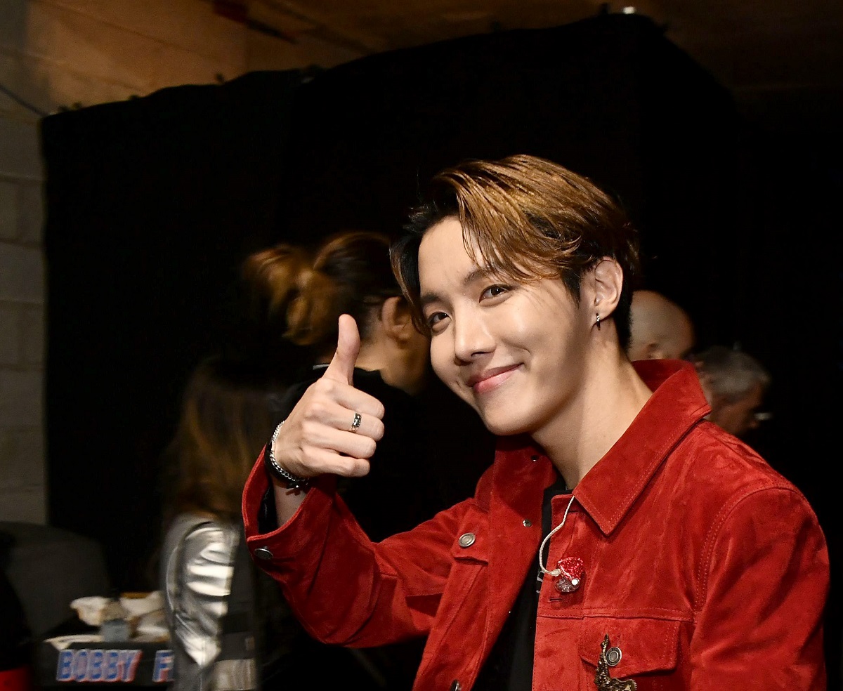 Jungkook îmbrăcat în roșu arătând semnul OK la cameră
