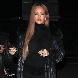 Rihanna îmbrăcată în negru și machiată în timp ce își ține telefonul în mână