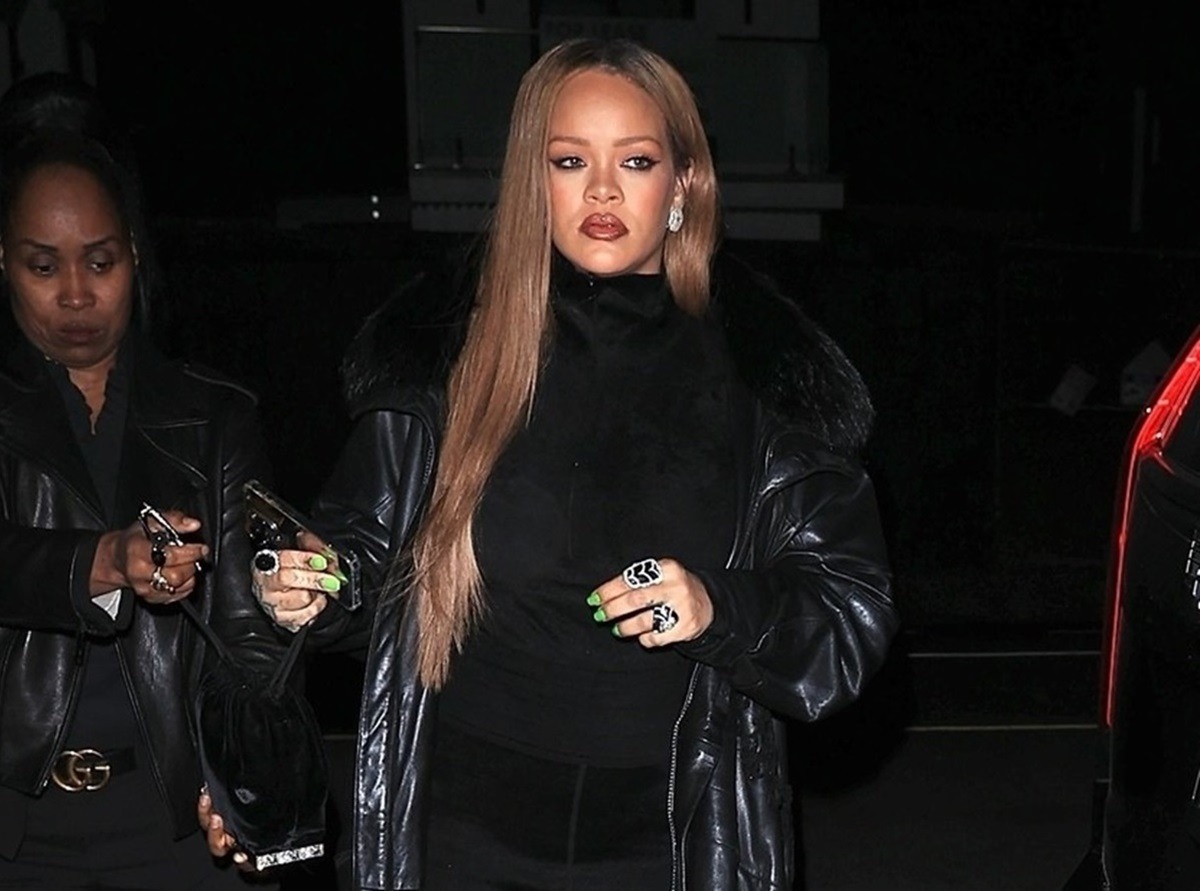 Rihanna îmbrăcată în negru și machiată în timp ce își ține telefonul în mână
