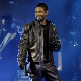 Usher îmbrăcat în negru în timp ce se afla pe scenă în fața unui microfon