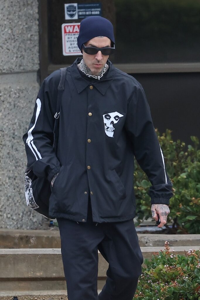 Travis Barker, în haine închise la culoare, cu căciulă în cap, pe stradă
