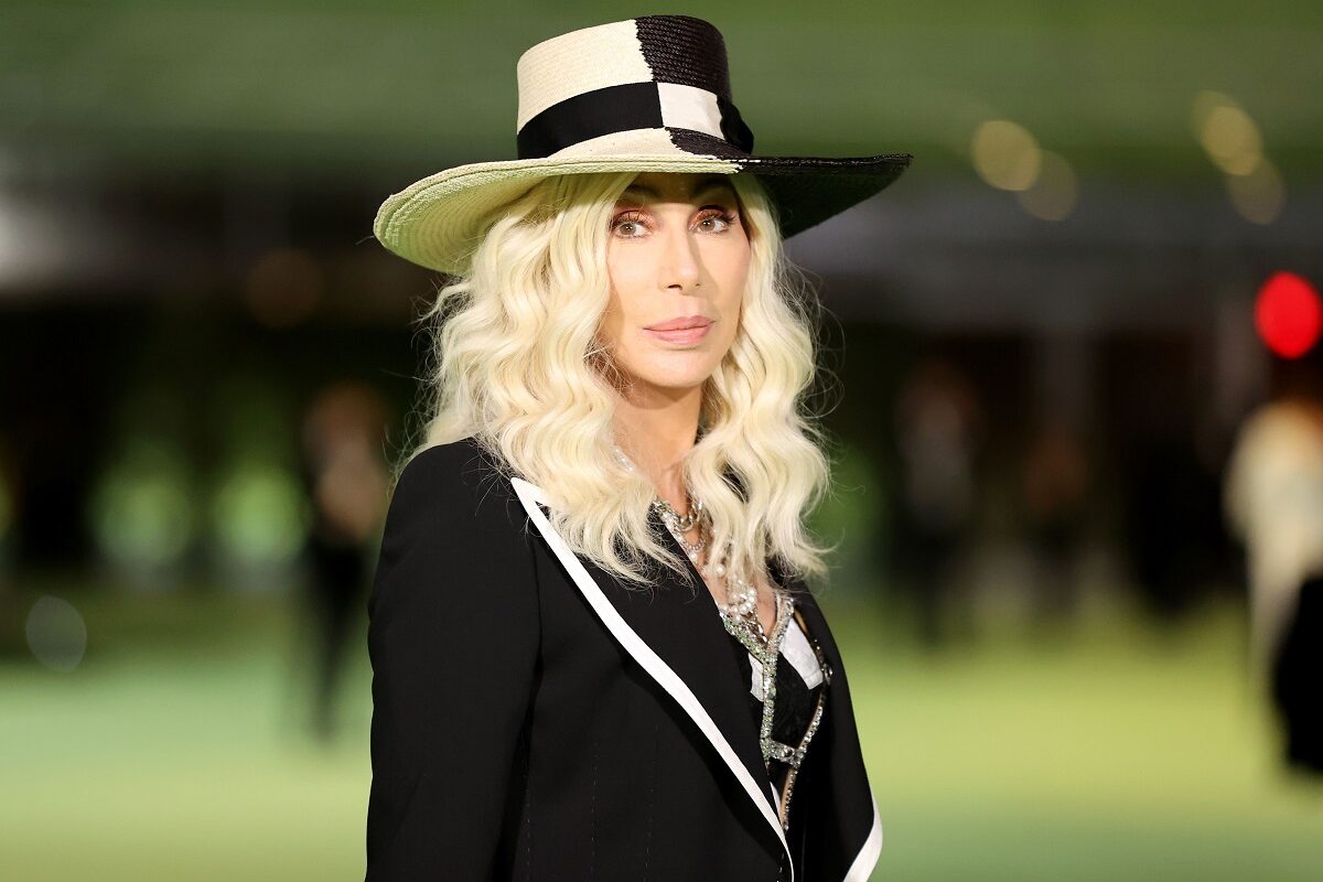 Cher blondă îmbrăcată în negru cu o pălărie în cap