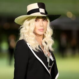Cher blondă îmbrăcată în negru cu o pălărie în cap