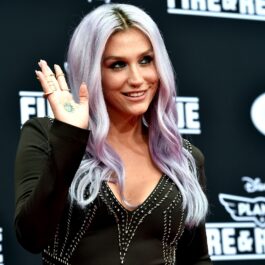 Kesha îmbrăcată într-o rochie neagră cu decolteu în timp ce salută fanii