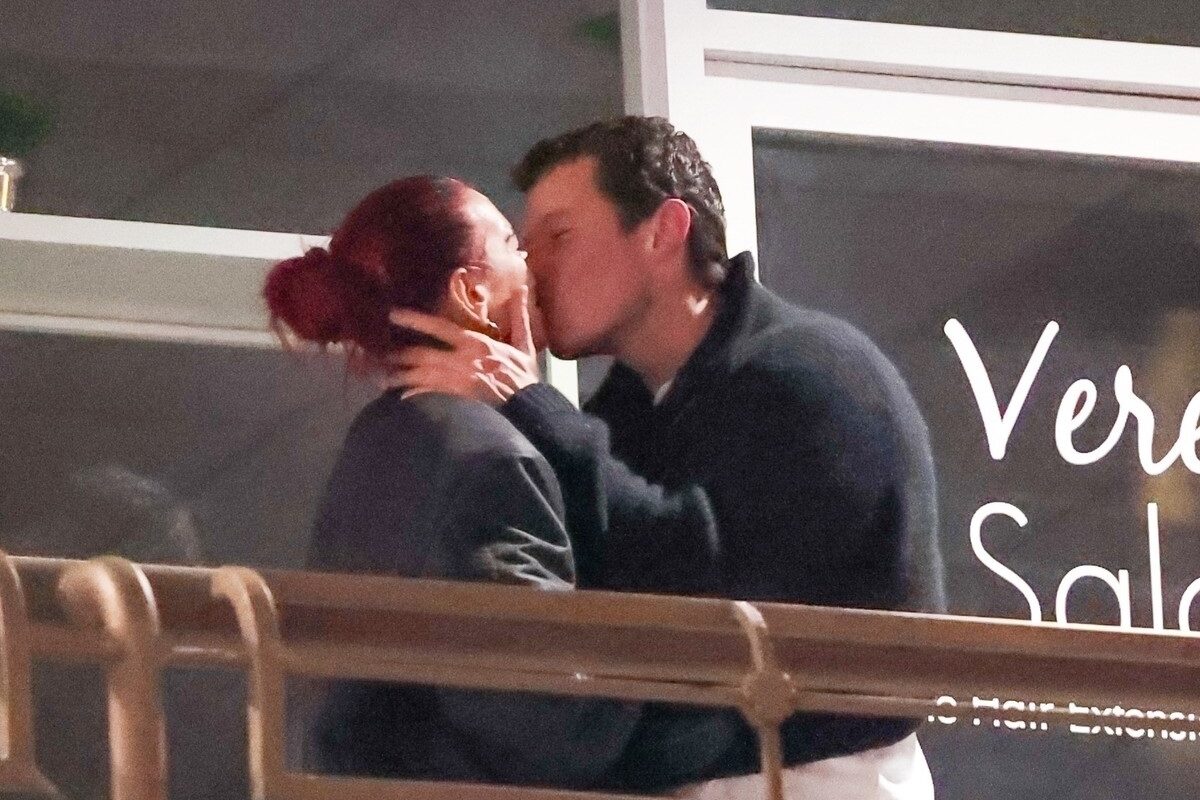 Dua Lipa și Callum Turner îmbrăcați casual în negru în timp ce se sărută pe un balcon