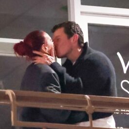 Dua Lipa și Callum Turner îmbrăcați casual în negru în timp ce se sărută pe un balcon