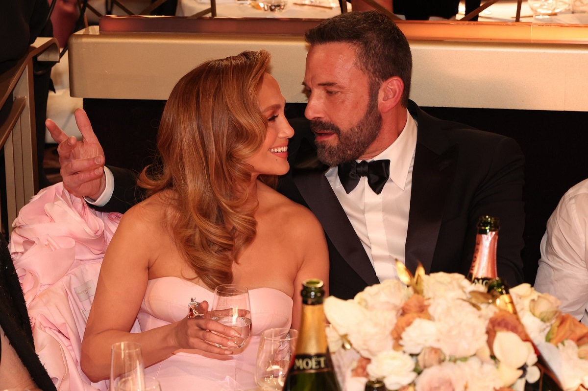 Jennifer Lopez și Ben Affleck îmbrăcați elegant în timp ce discută și servesc șampanie