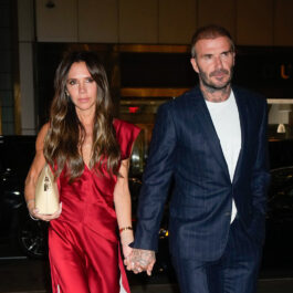 Vedetele au sărbătorit Anul Nou cu stil. Aici David și Victoria Beckham participă la un eveniment și se țin de mână. Ea poartă o rochie roșie și el un costum albastru