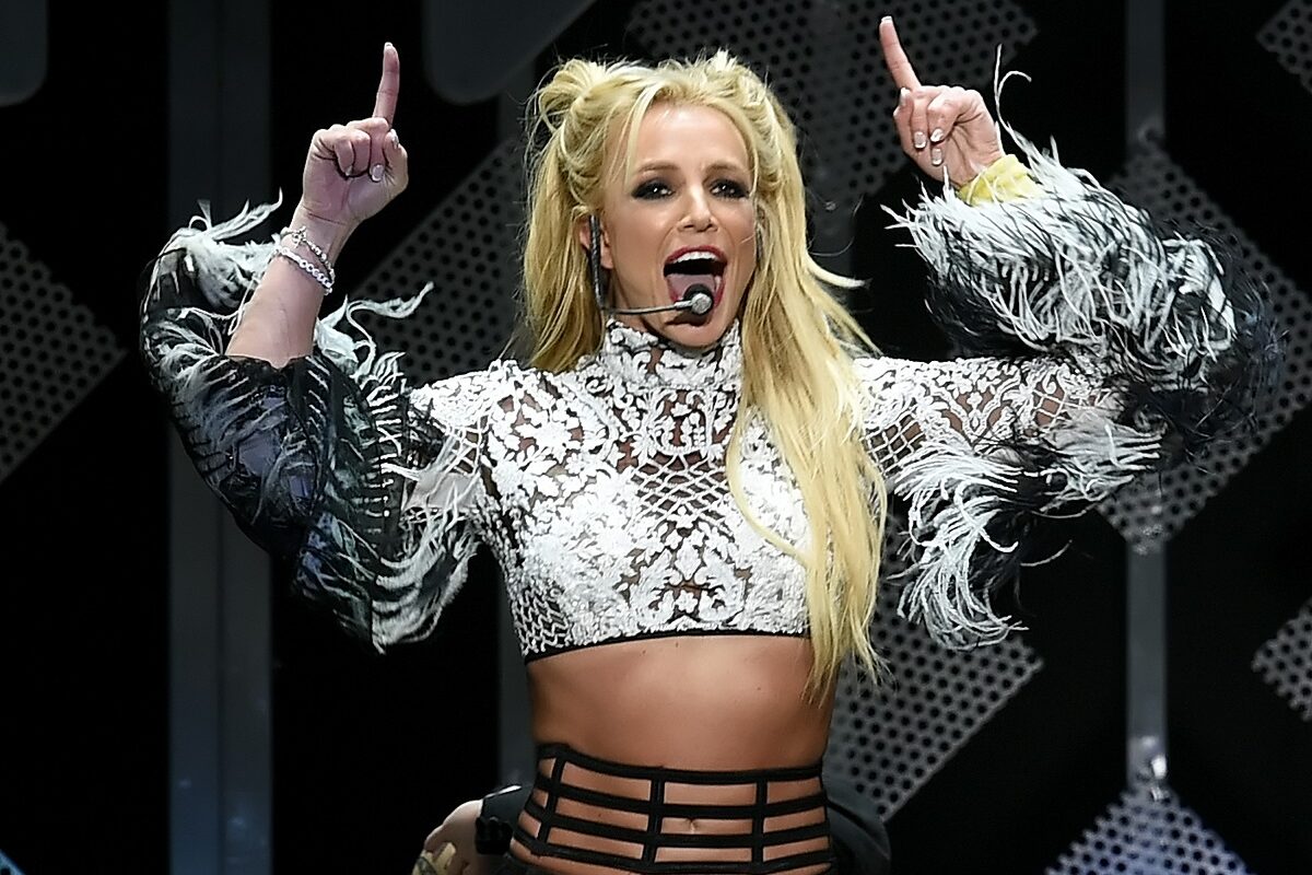 Britney Spears îmbrăcată într-un top argintiu în timp ce cântă și dansează