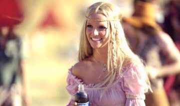 Britney Spears îmbrăcată într-o rochie roz în timp ce ține o sticlă de suc în mână