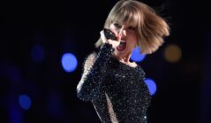 Taylor Swift îmbrăcată într-o rochie cu pietricele negre strălucitoare în timp ce cântă la microfon