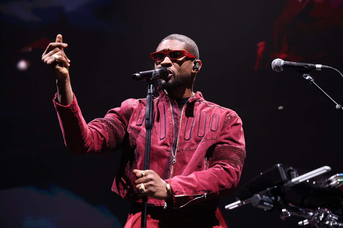 Usher îmbrăcat într-o ținută roșie în timp ce cântă la microfon