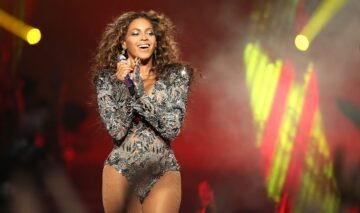 Beyoncé îmbrăcată într-un body strălucitor cu mâneci lungi în timp ce cântă și dansează