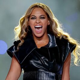 Beyoncé îmbrăcată într-o ținută neagră strălucitoare din latex în timp ce cântă