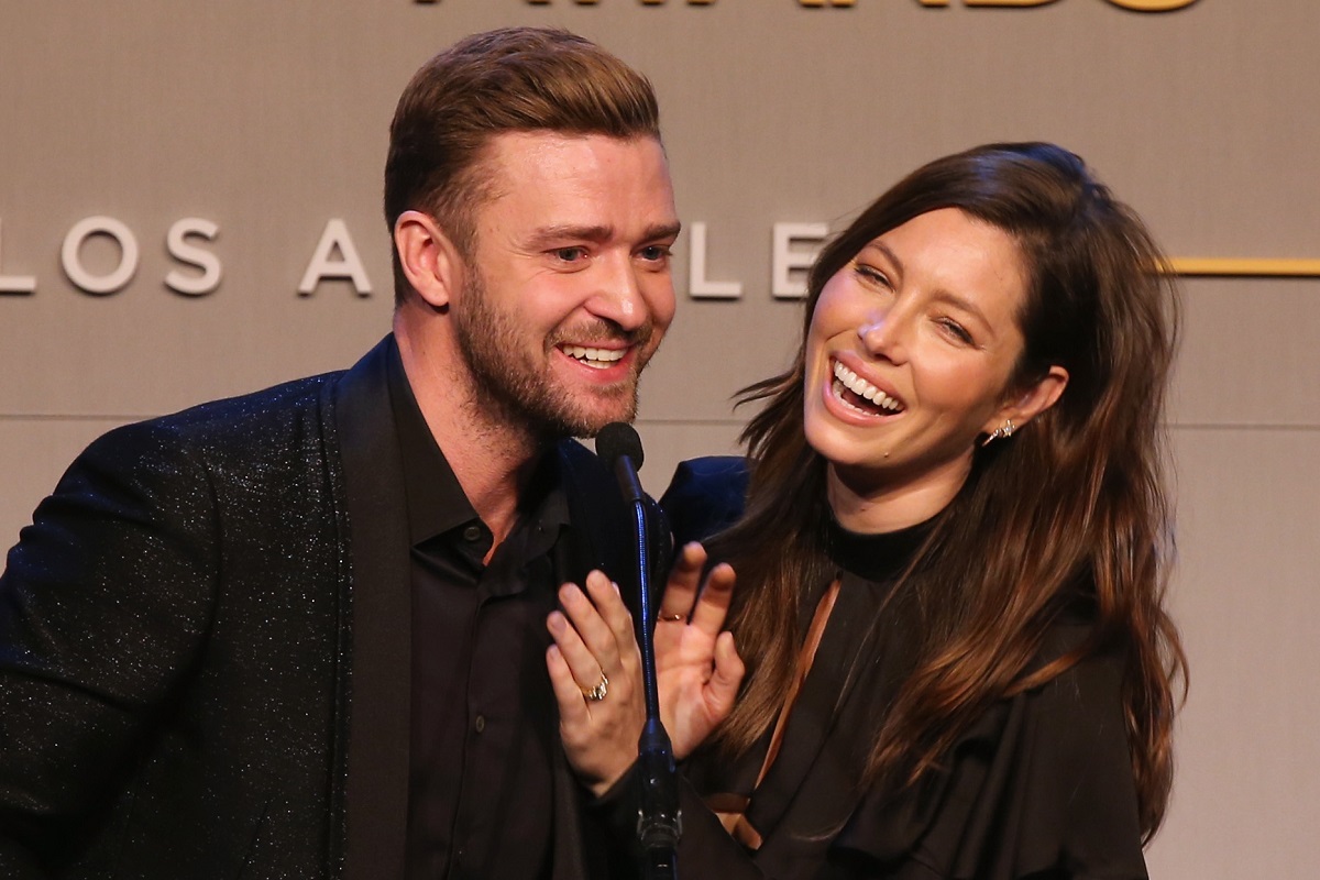 Justin Timberlake și Jessica Biel îmbrăcați în ținute negre în timp ce râd și vorbesc la microfon
