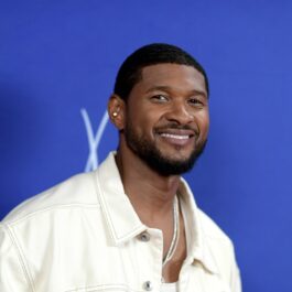 Usher îmbrăcat cu o jachetă albă și purtând un lănțișor la gât