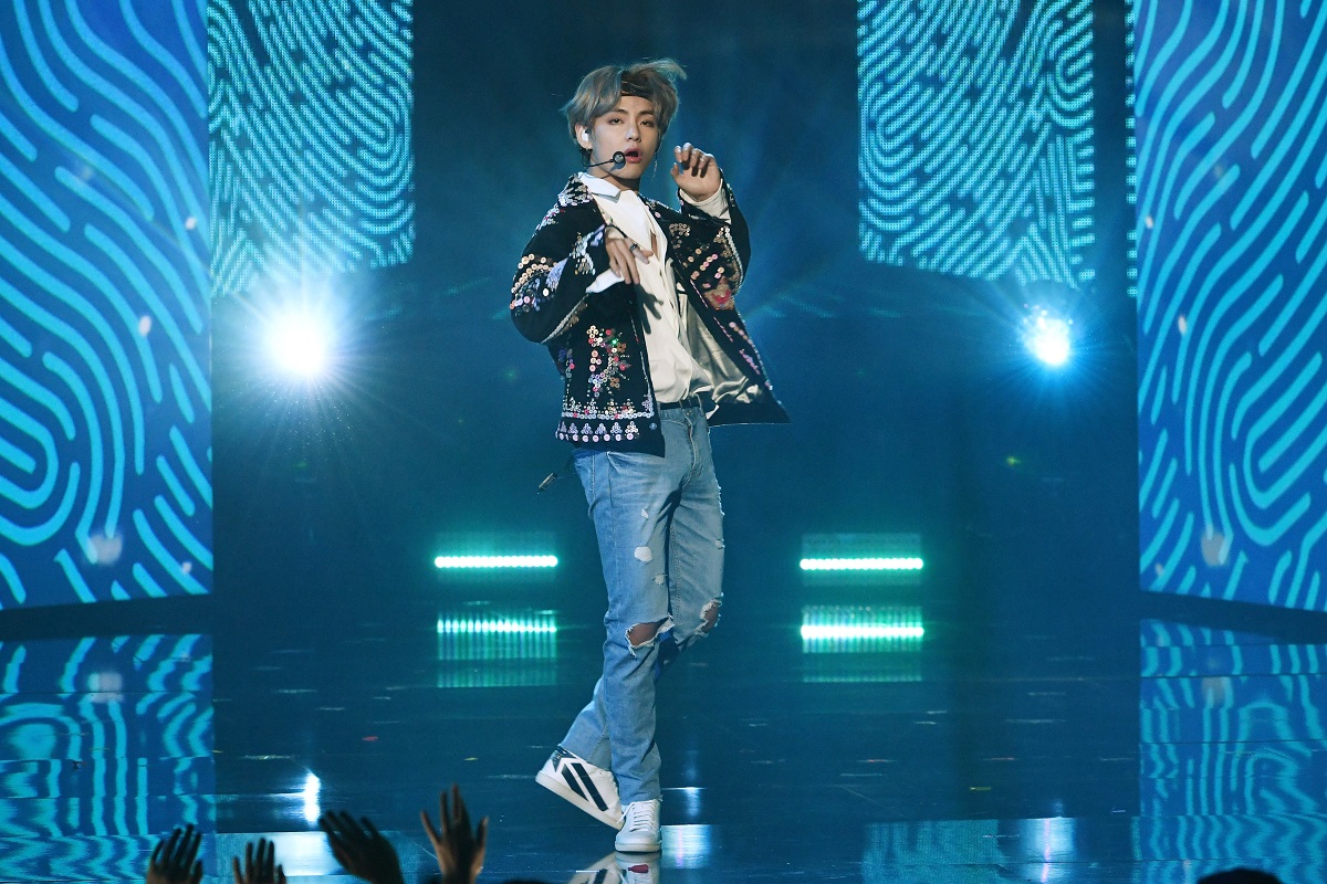 V de la BTS îmbrăcat casual cu blugi și o jachetă în timp ce dansează