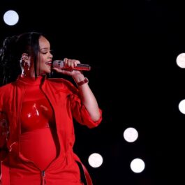 Rihanna îmbrăcată într-o ținută complet roșie în timp ce cântă la microfon