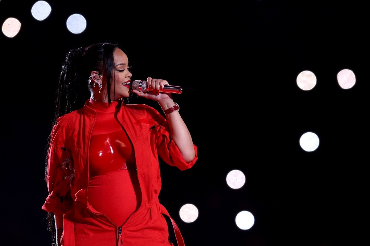Rihanna îmbrăcată într-o ținută complet roșie în timp ce cântă la microfon