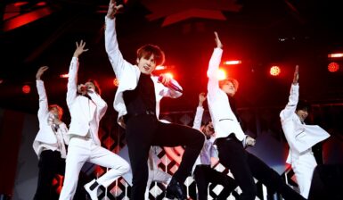 Membrii trupei BTS îmbrăcați în ținute alb și negru în timp ce cântă și dansează pe scenă