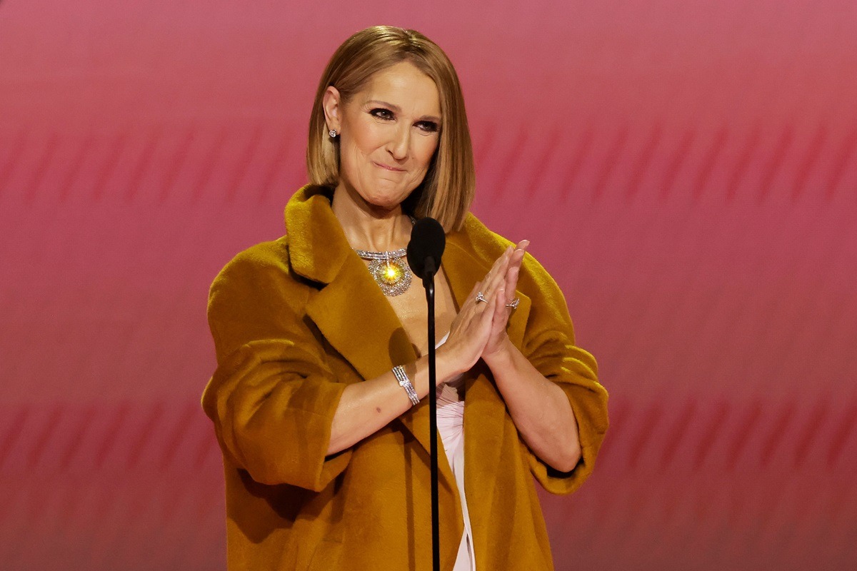 Celine Dion îmbrăcată într-un palton auriu în timp ce aplaudă după un discurs