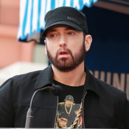 Eminem îmbrăcat casual cu un hanorac negru și o șapcă asortată